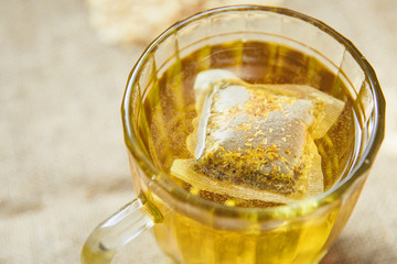 Glass cup with yellow tea with chamomile on light background