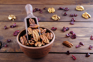 Pecan in a scoop and a bowl and a wooden background.
