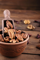 Pecan in a scoop and a bowl and a wooden background.