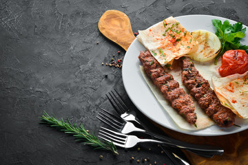 Lamb Kebab. Pita bread and spices. On a black background. Top view.