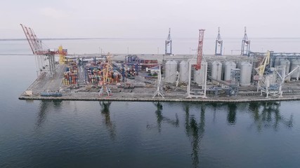 Aerial of Odessa business seaport with square dock, cranes and barrels in summer
