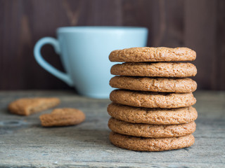 Healthy oatmeal burger. Oatmeal cookie stack, white cup on wooden background. Useful sweets closeup