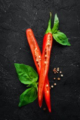Red chili and basil. On a black background. Top view. Free copy space.