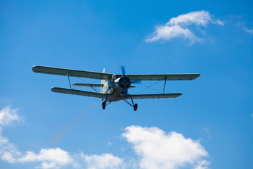 An old plane like a corn duster flying in the sky on a sunny day
