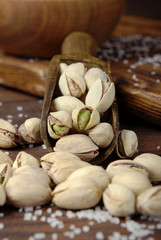 Fototapeta na wymiar Salted pistachios in a scoop on a wooden background.