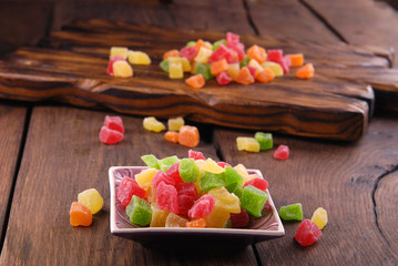 Multicolored dry fruits in a bowl on a wooden table.

