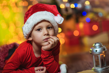 Boy posing in red hat near the Christmas tree