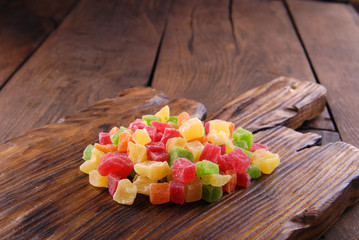 Multicolored dry fruits in a bowl on a wooden table.
