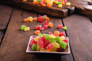 Multicolored dry fruits in a bowl on a wooden table.
