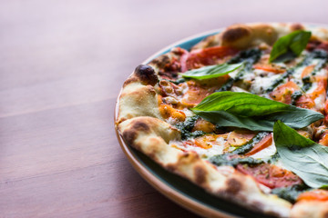 Pizza Margarita or Margherita on wooden table background, top view. Pizza with Tomatoes, Fresh Basil, Mozzarella Cheese, Pepper and Spices close up. Sliced Italian Pizza. 