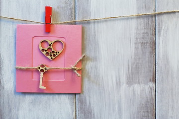 Handmade. Stylized heart and key on jute cord on pink paper background. Light natural wooden background.