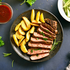 Medium rare roast beef with potato wedges