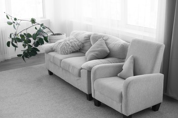 sofa with pillows. couch and chair. gray sofa next to the window. interior of the room