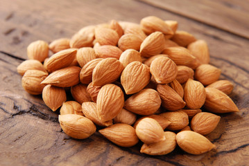 Dry apricot kernels on a wooden background.