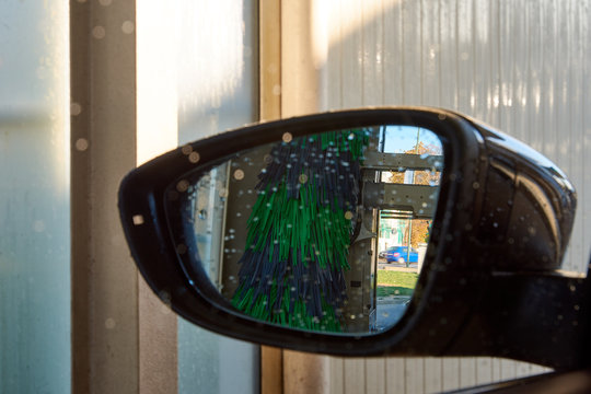 Close-up photo of a rear view mirror inside a car wash with water drops