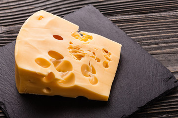 Piece and slices of cheese on a wooden background
