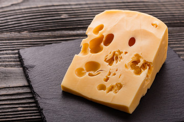 Piece and slices of cheese on a wooden background