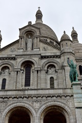 Fototapeta na wymiar Basilica of the Sacred Heart (Sacre Coeur). Paris, France, Montmartre. Facade with statues, archs, dome and towers. Rainy day, grey sky.