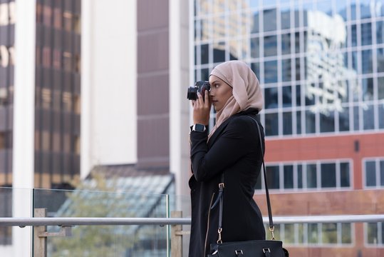 Woman clicking photo in digital camera at balcony