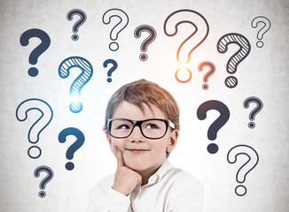 Thinking little boy, question marks on wall