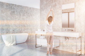 Concrete bathroom corner, tub and sink, woman