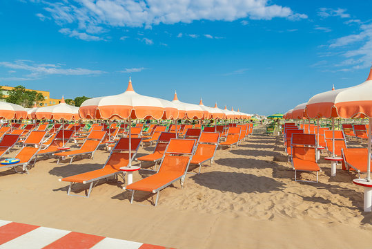 Umbrellas and chaise lounges on the beach of Rimini in Italy.