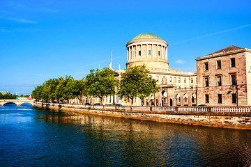 Obraz premium Budynek czterech kortów nasłonecznionych w Dublinie w Irlandii z rzeką Liffey