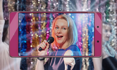 Portrait of young woman singing at karaoke on cellphone screen, smart device concept