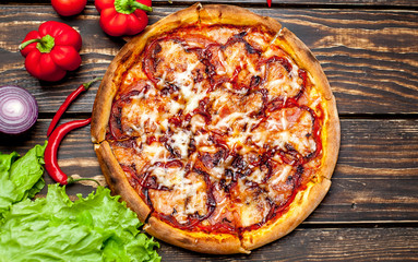 pizza on wooden table with ingredients, tomatoes, pepper, onion