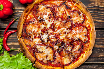 pizza on wooden table with ingredients, tomatoes, pepper, onion