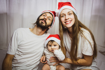 Fototapeta premium young family with baby having fun with santa hats