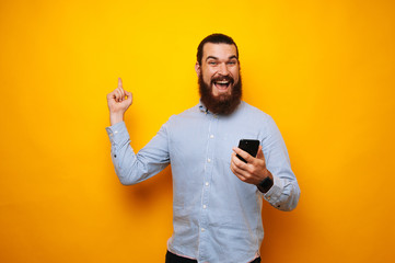 Photo of happy bearded man in shirt and pointing to up