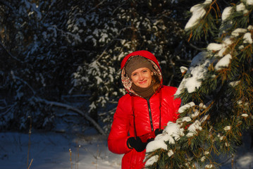 Blonde girl in red scarf and coat walking at park on winter day.