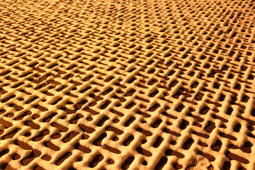 Beautiful geometrical pattern of snow on the paving tiles a night in the yellow light of the winter - background, texture in perspective