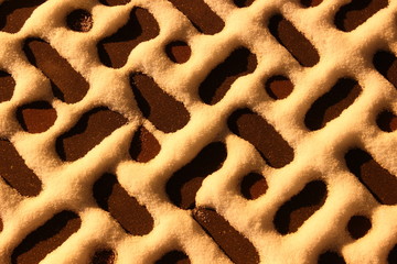 Beautiful geometrical pattern of snow on the brown paving tiles a night in the yellow light of the winter - close up background, texture