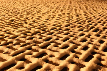 Beautiful geometrical pattern of snow on the paving tiles a night in the yellow light of the winter - background, texture in perspective