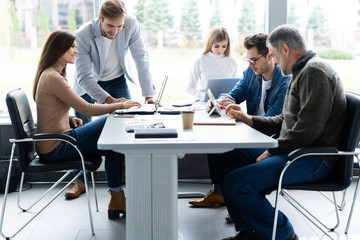 Working day. Group of young modern people in smart casual wear discussing business while working in the creative office.