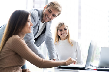Working day. Group of young modern people in smart casual wear discussing business while working in the creative office.