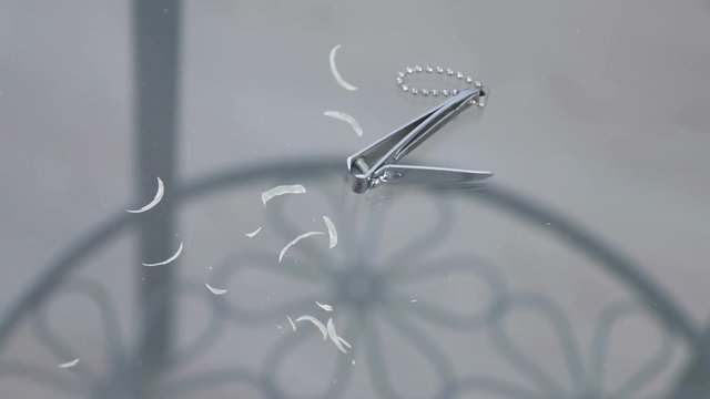 Trimmed nails on the glass table with clippers.