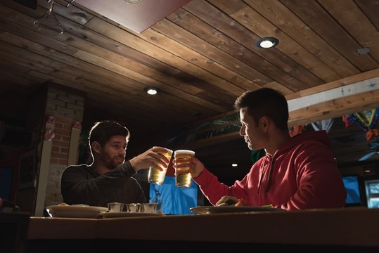 Friends toasting beer glasses in pub