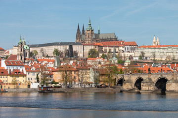 Naklejka na ściany i meble View of Prague Castle, Charles bridge and Vltava river. Beautiful Prague cityscape with classic red roofs and famous gothic church St. Vitus Cathedral and Baroque Church of St Nicholas.
