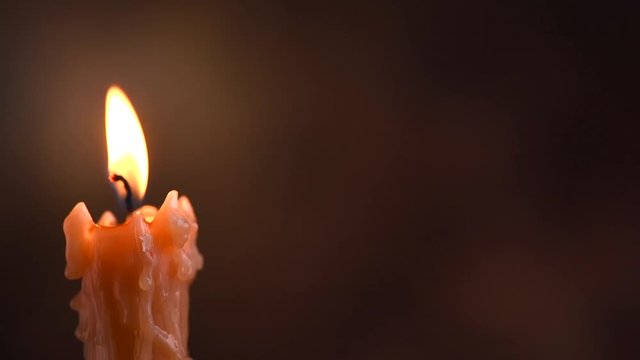 Candle flame closeup on dark background. Candle light border design. Melted wax candle burning at night. Rotation. 3840X2160 4K UHD video footage