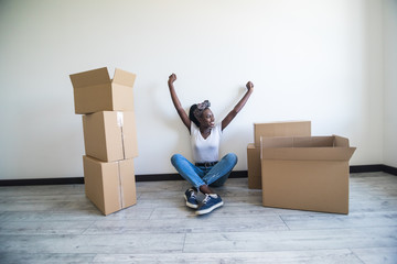 People, moving new place and repair concept - happy african american young woman sitting in new...