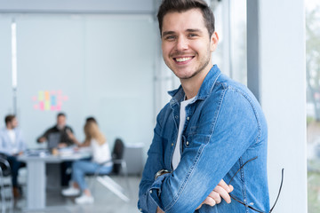 Smiling businessman in denim shirt looking at camera in office.