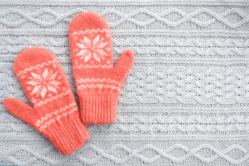Warm woolen mittens on knitted background. Living coral creative and moody color of the picture. Color of the 2019 year.