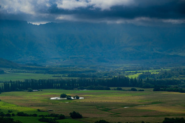 Aerial view overlooking a tropical valley with the sun streaking through the clouds on the island...