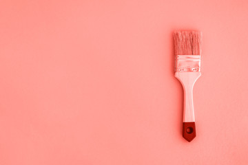 Painting brush on living coral color background.