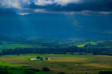 Aerial view overlooking a tropical valley with the sun streaking through the clouds on the island...