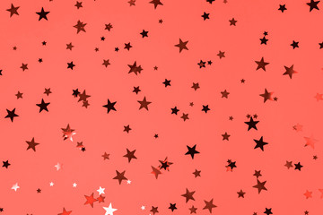 Delicate glitter star confetti on living coral background. Color of the 2019 year.