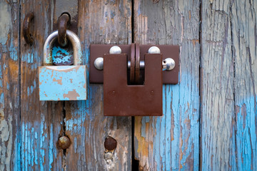 two different locks on old wooden garage door, peeling paint, in Warsaw, Poland